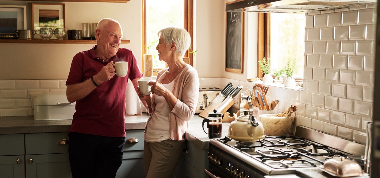 A mature couple drinking coffee together in a kitchen.