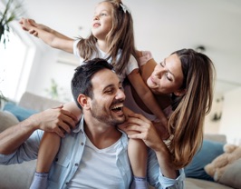 A young family playing together on a couch.