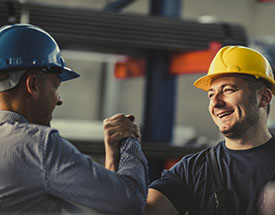 Image of two men in hard hats clasping hands