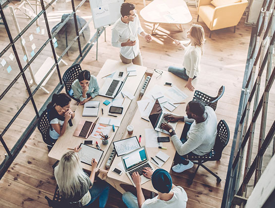 Overhead image of people around a table working on laptops