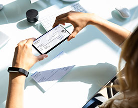 Woman taking a photo of a check with her mobile phone