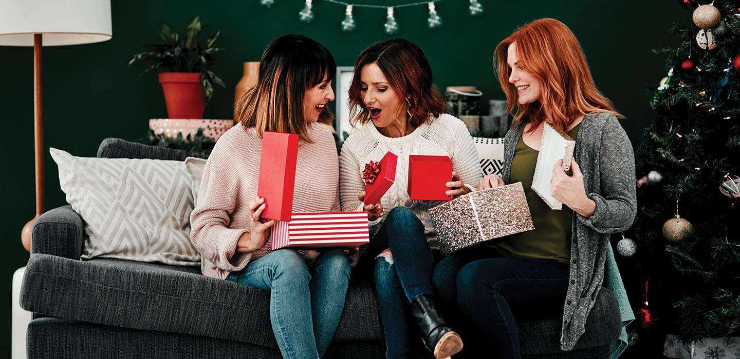 Group of women sitting on a couch and opening presents