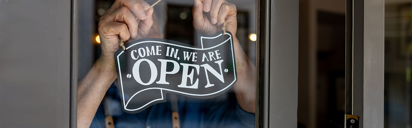 Shop owner hanging sign that reads Come In, We Are Open