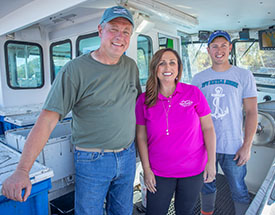 Community banker standing on boat with lobstermen