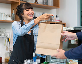 Shop owner handing over a bagged purchase to customer