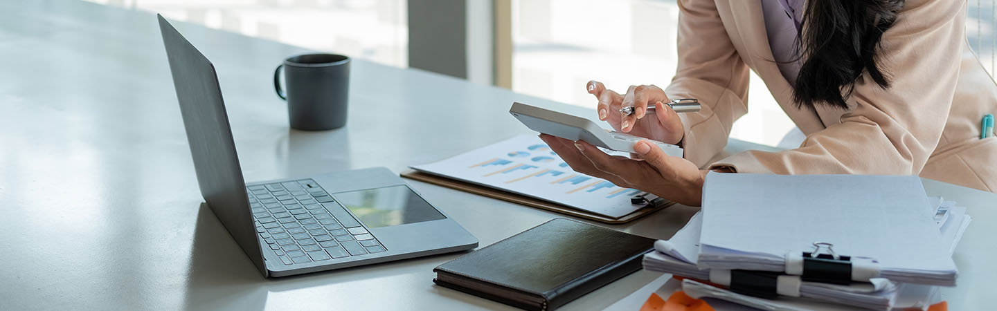 Lawyer using a calculator among a stack of contracts