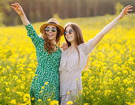 Two joyful women standing in a field of yellow flowers
