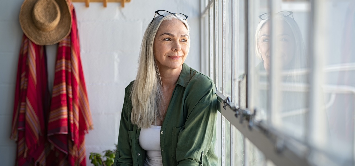 A woman seated near a large window.