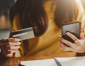 Woman holding a debit card and looking at a smartphone