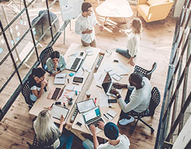 Overhead image of people sitting around a table working on laptops