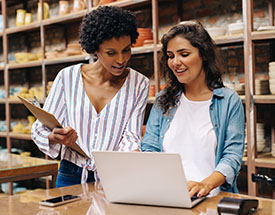 Two business women looking at laptop in pottery store
