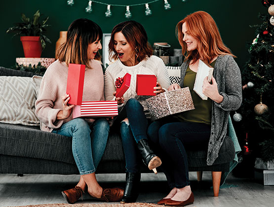 Group of women sitting on a couch and opening presents