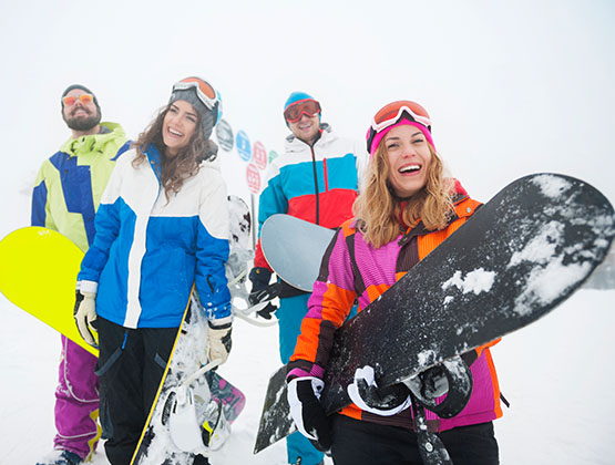 Group of smiling friends holding snowboards in the snow