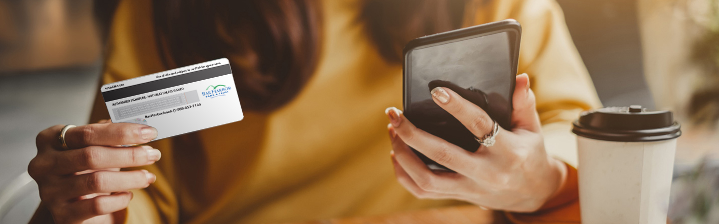 Woman holding a smartphone and a BHBT debit card