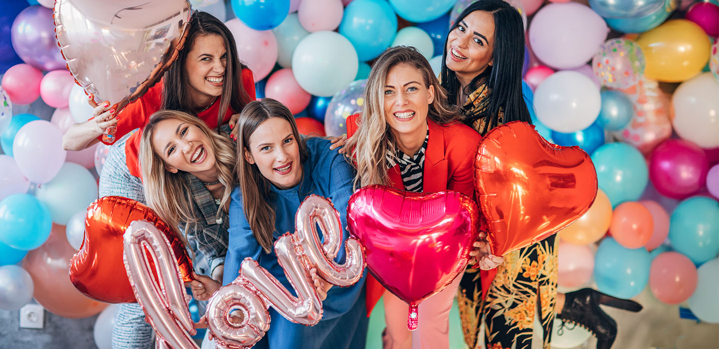 Women smiling and holding heart balloons