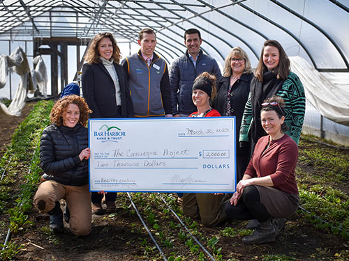 Employees present a check to the Cornucopia Project
