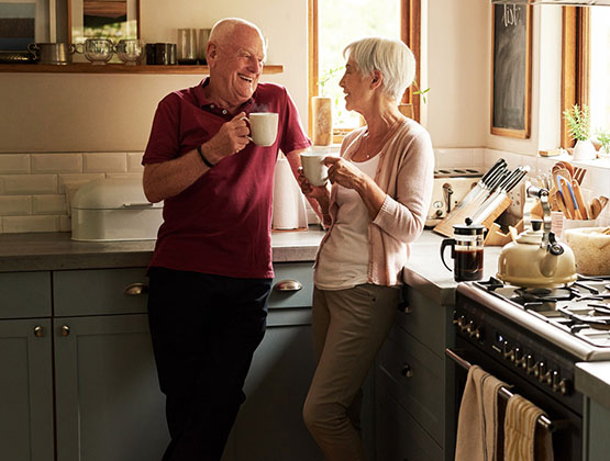 An older couple enjoying cups of coffee in a kitchen