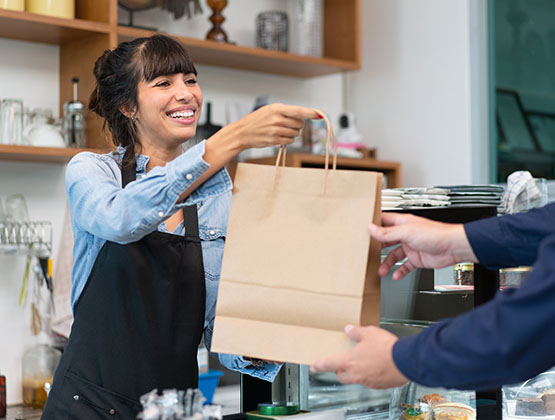 Shop owner handing a bagged package to a customer