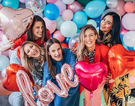 Women smiling and holding heart balloons
