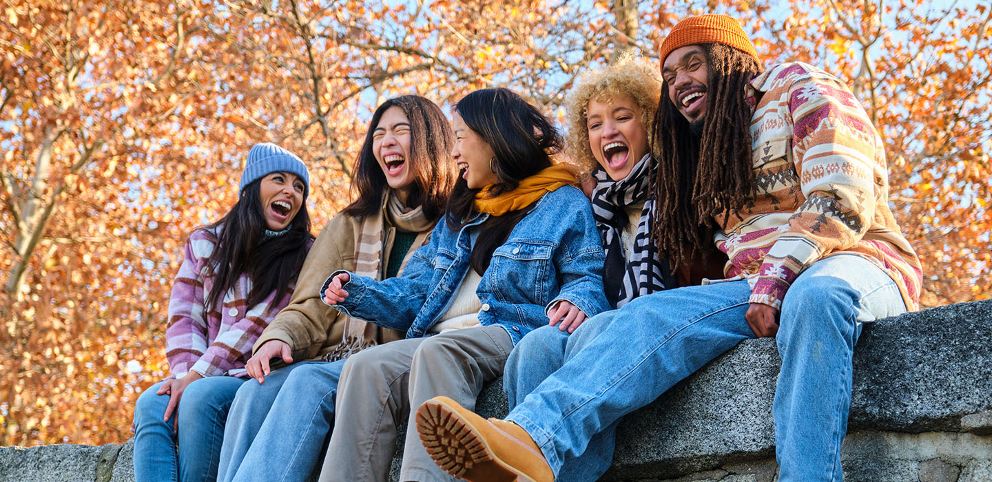 Friends laughing while surrounded by Fall foliage