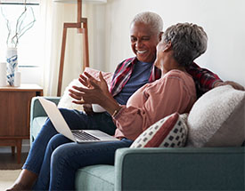 Couple sitting on a couch and using a laptop