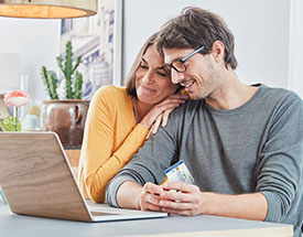 Woman and man looking at a laptop while holding a Bar Harbor Bank & Trust CashBack Debit Mastercard